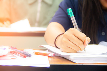 University students do quiz, test or studies from the teacher in a large lecture room. Students in uniform attending exam classroom educational school.