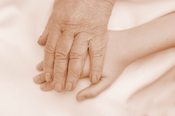 The hand of an old grandmother holds the hand of a child. Concept of help, care, support.