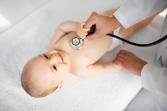 Medicine, Healthcare And Pediatrics Concept - Close Up Of Female Doctor With Stethoscope Listening To Baby Girl's Patient Heartbeat Or Breath At Clinic Or Hospital