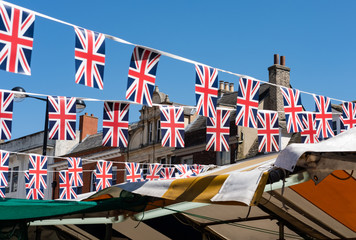 Isolated image of Union Jack Royal Wedding bunting seen hanging in an outside market during the day of the Royal Wedding. Houses are seen in the background.