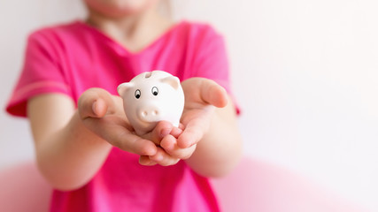 Pink piggy bank on children hands. Close up, selective focus.