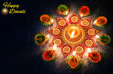 Diwali clay lamps with traditional rangoli pattern on dark background