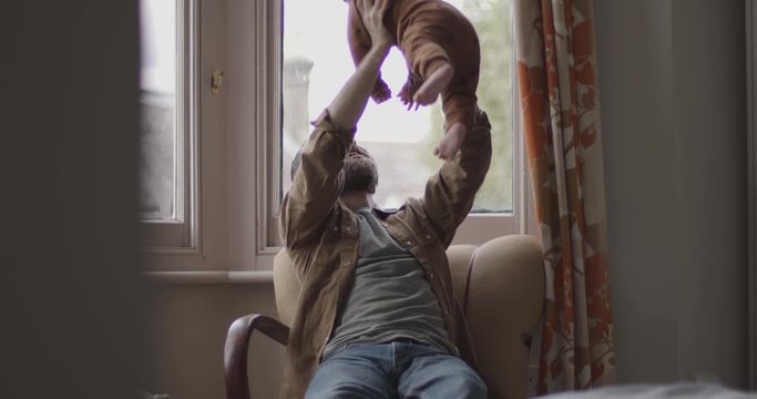 Single father playing with baby boy in chair