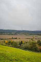 herbstliche Landschaft im Nebel, im Hintergrund ein einzelnes Windkraftrad