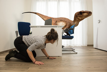 A young employee hides from a velociraptor in the office where she works - obrazy, fototapety, plakaty