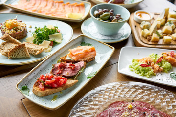 Bruschetta with beef, tomatoes and salmon.. Variety of dishes on the table. Various snacks and antipasti on the table. Restaurant menu. Italian cuisine