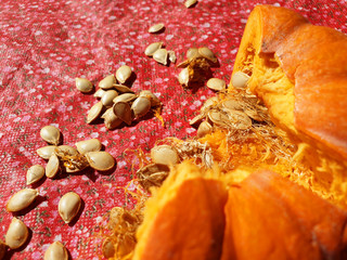 Broken pumpkin with seeds on the red surface. Close up, top view.