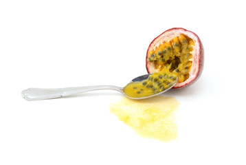 Spoon scooping out seeds from half a purple passion fruit