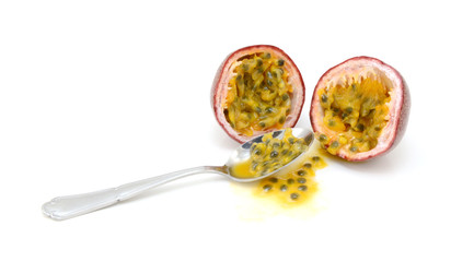 Spoon scooping out pulp and seeds from a passion fruit