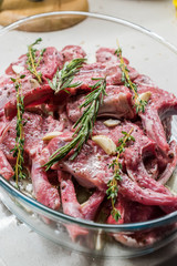 Raw Marinated Lamb Chops with Rosemary, Olive Oil and Garlic in Glass Bowl.
