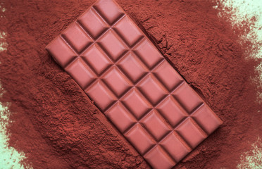 Milk chocolate bar on a cocoa powder pile. Chocolate ingredients