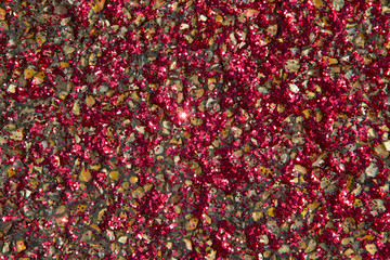 Sparkling red glitters on pebblestone road