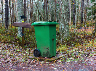 Garbage can in the forest near by a direction sign