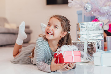 Careless, smiling small female enjoying Christmas time and presents.