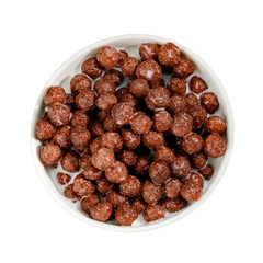 Chocolate cereal balls with milk in a cup, top view