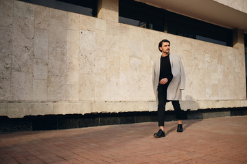 Young attractive man in coat walking outdoor