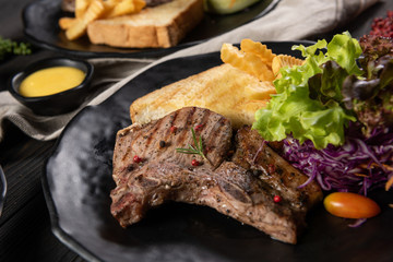 The ribs of the cow grilled until cooked served with garlic bread, french fries and a mixed salad. Everything is placed on a matt black plate. Complete with nutrients that are suitable for good meals.