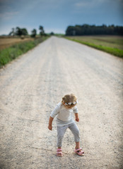 Little girl on the road in countryside. Summer.