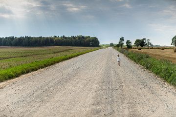 Little girl on the road in countryside. Summer.