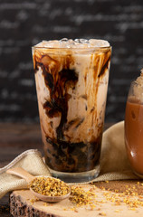 Ice chocolate, toppings by choco lava beside in a tall of clear glass on dark gray real wood and chopping board. Decoration with thai tea leaf  in front. Popular drink to quench thirst to cool down
