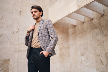 Young attractive man in checkered jacket thoughtfully looking away outdoor