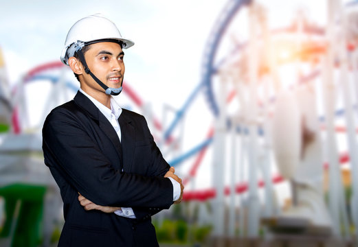 Engineer or Businessman standing on the blurred image of roller coaster in attraction park.