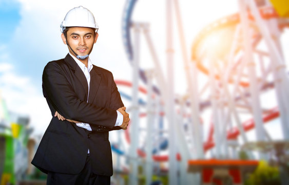 Engineer or Businessman standing on the blurred image of roller coaster in attraction park.