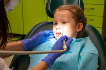 Little Caucasian girl treats teeth at the dentist