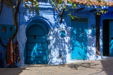 Narrow streets and blue painted houses of Chefchaouen city, Morocco. Most of the streets full of handmade colorful crafts,carpets and souvenir hanged to the walls of the blue houses.