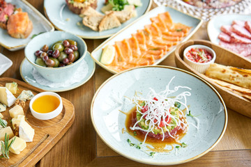 The tuna tartare in the restaurant. Variety of dishes on the table. Various snacks and antipasti on the table. Restaurant menu. Italian cuisine
