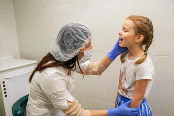 Dentist examines teeth of little Caucasian girl