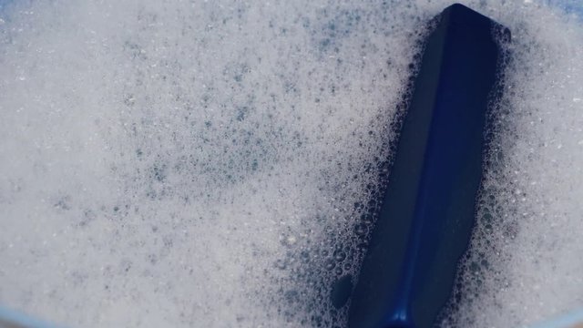 A blue can of shampoo floats in foamy water. The concept of cleanliness and personal care.