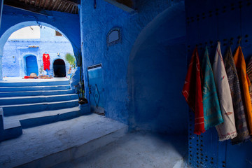 Narrow streets and blue painted houses of Chefchaouen city, Morocco. Most of the streets full of handmade colorful crafts,carpets and souvenir hanged to the walls of the blue houses.