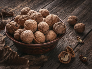Pile of walnuts in a clay dish on a wooden table