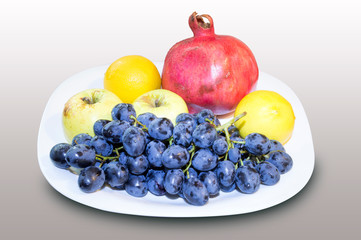 pomegranate, grape with apple and lemon in a white plate