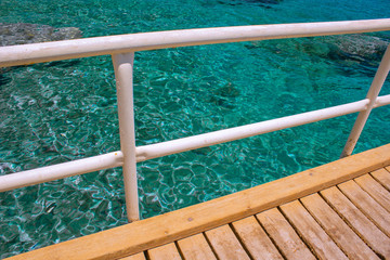 Fototapeta premium tropic outdoor environment wooden pier in poor Asian dock aquamarine transparent ripple water background surface with coral reefs bottom view on background