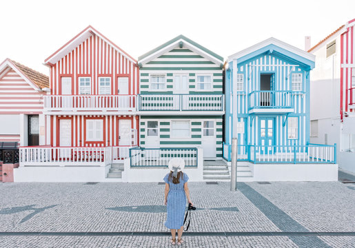 Rear view of woman with camera in front of striped houses, Costa Nova, Portugal