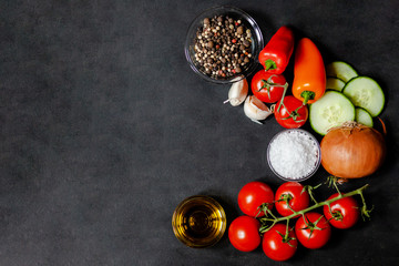 Ingredients for traditional homemade cold summer soup gazpacho: tomato, cucumber, pepper, olive oil, garlik, onion, salt. Fresh and healthy lunch. Black background, flatlay, top view, copy space