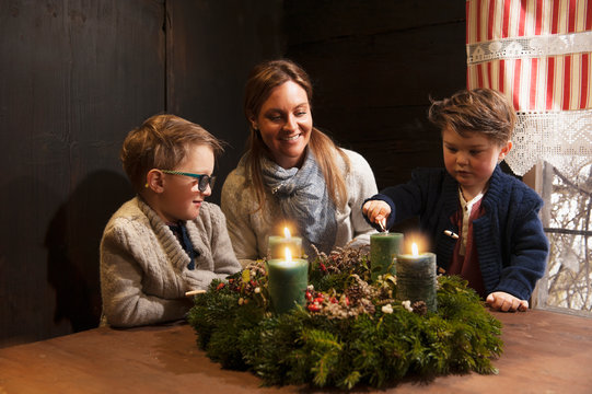 Mother and her two little sons lightning candles on a Advent wreath