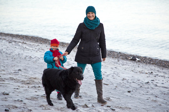 Germany, Schleswig-Holstein, Kiel, mother and daughter walking with Labrador along the beach