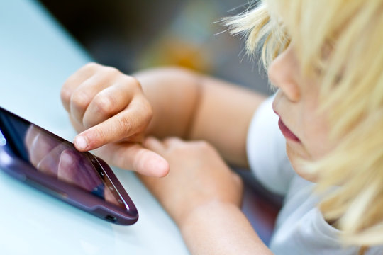Germany, Kiel, Girl playing with smart phone, close up