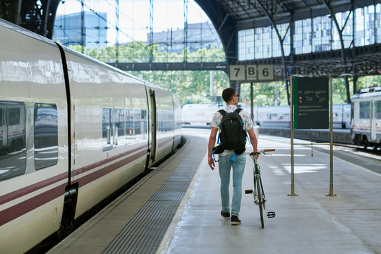 Man pushing bicycle through a station