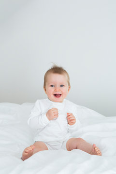Smiling baby girl sitting on bed