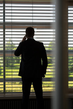 Germany, Hannover, Businessman talking on mobile phone in conference room