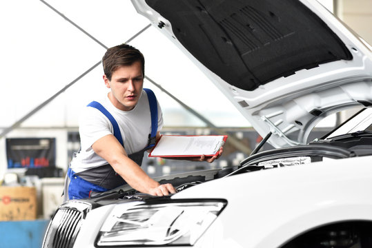 Mechanic examining engine of a car in a garage