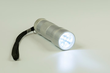 pocket metal flashlight with burning LEDs on a white background
