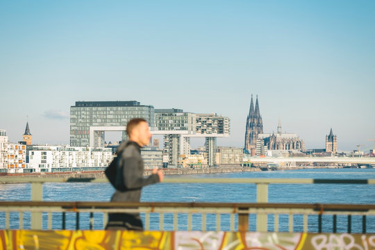 Germany, Cologne, Young man running at the riverside