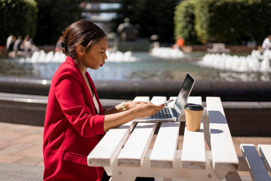 Businesswoman working on laptop outdoors, London, UK