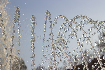 the water jet of the fountain froze in the air against a blue sky. clean water splashes in a city park.