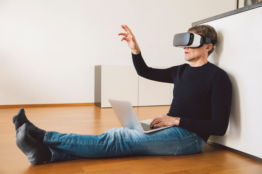 Man wearing virtual reality glasses using laptop
